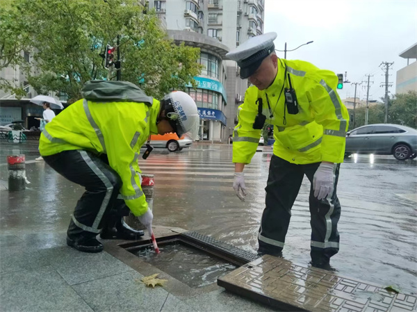 四大隊(duì)民警蘇張靈、輔警王志斌在牡丹江路寶林路積水點(diǎn)對(duì)下水道進(jìn)行清理。